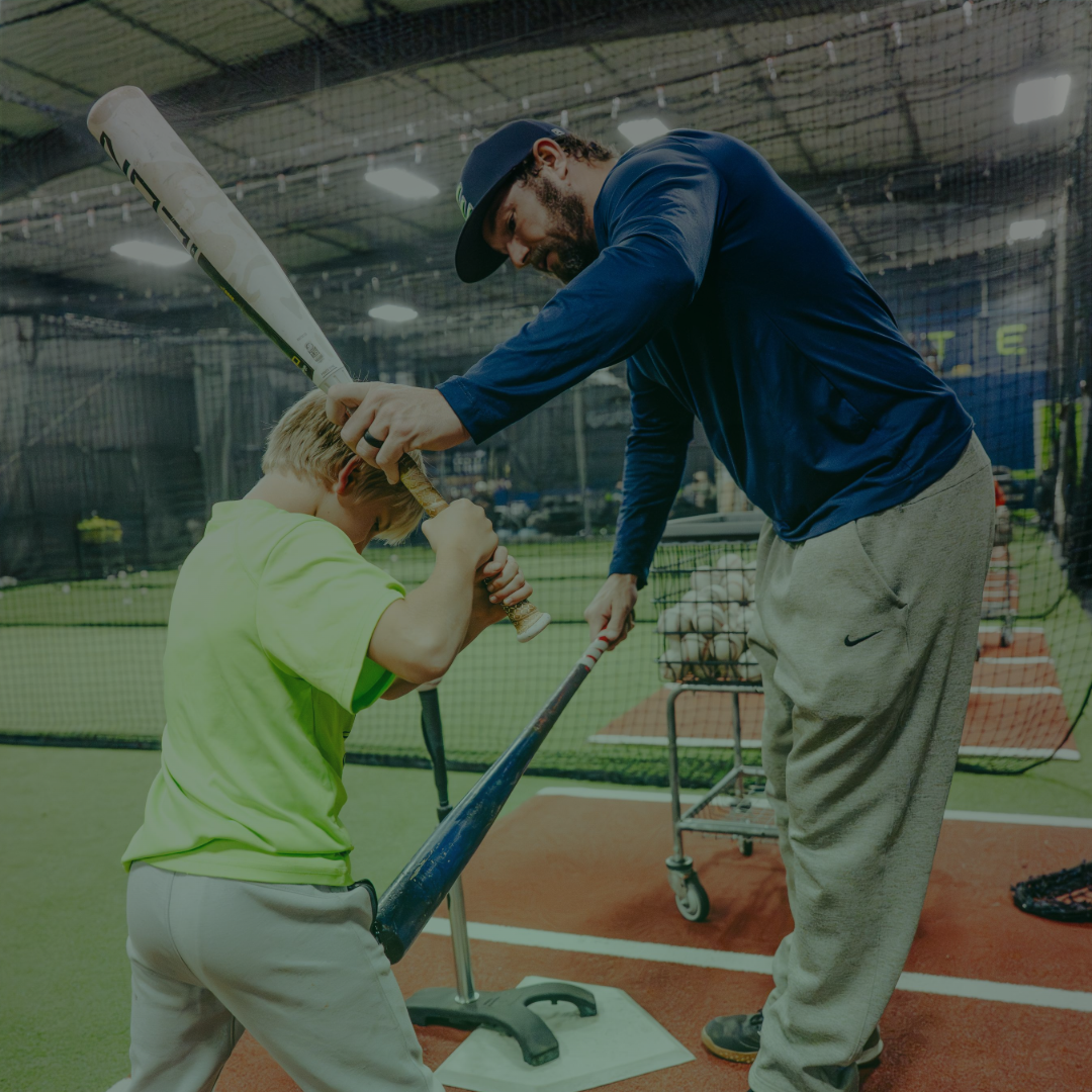 Coach helping a young baseball player refine their swing